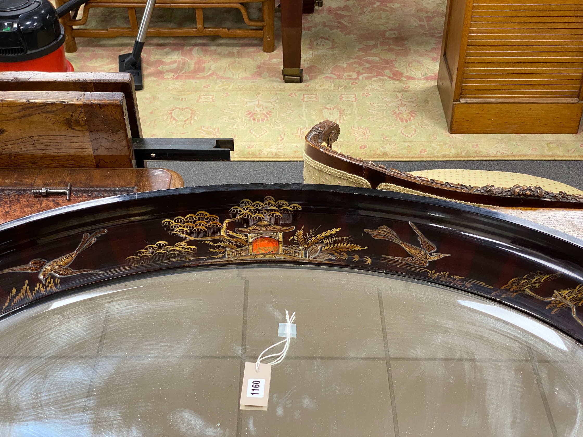 An early 20th century oval chinoiserie lacquered oval wall mirror, width 117cm, height 78cm